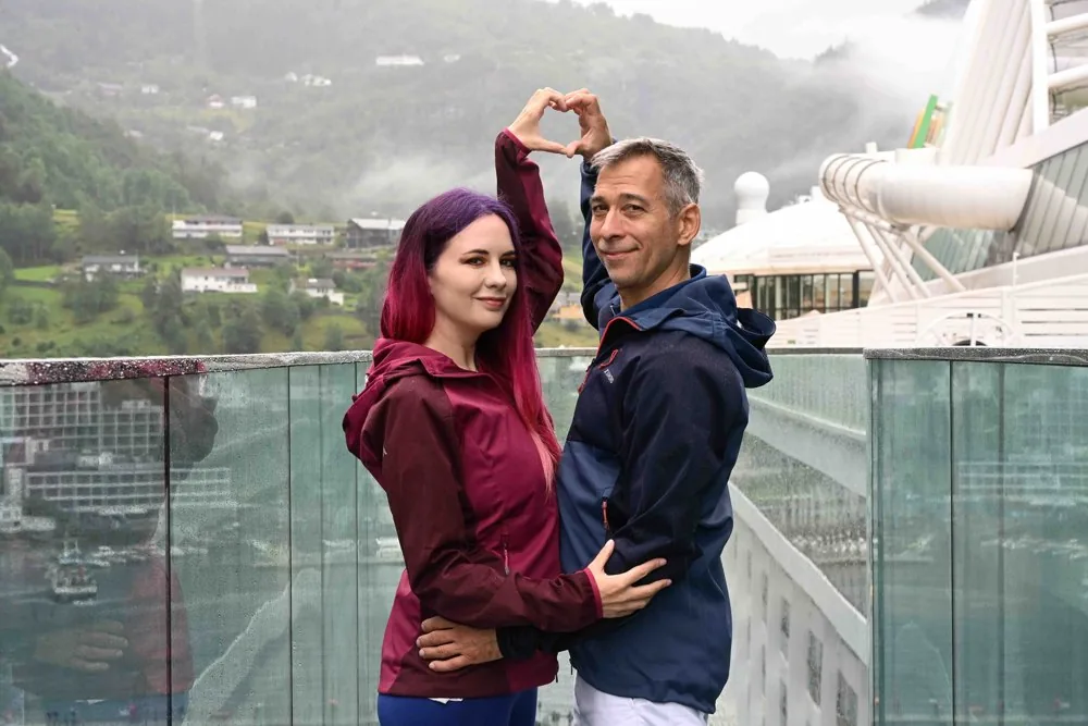 Isabella und Christian formen über dem Fjord ein Herz mit den Händen